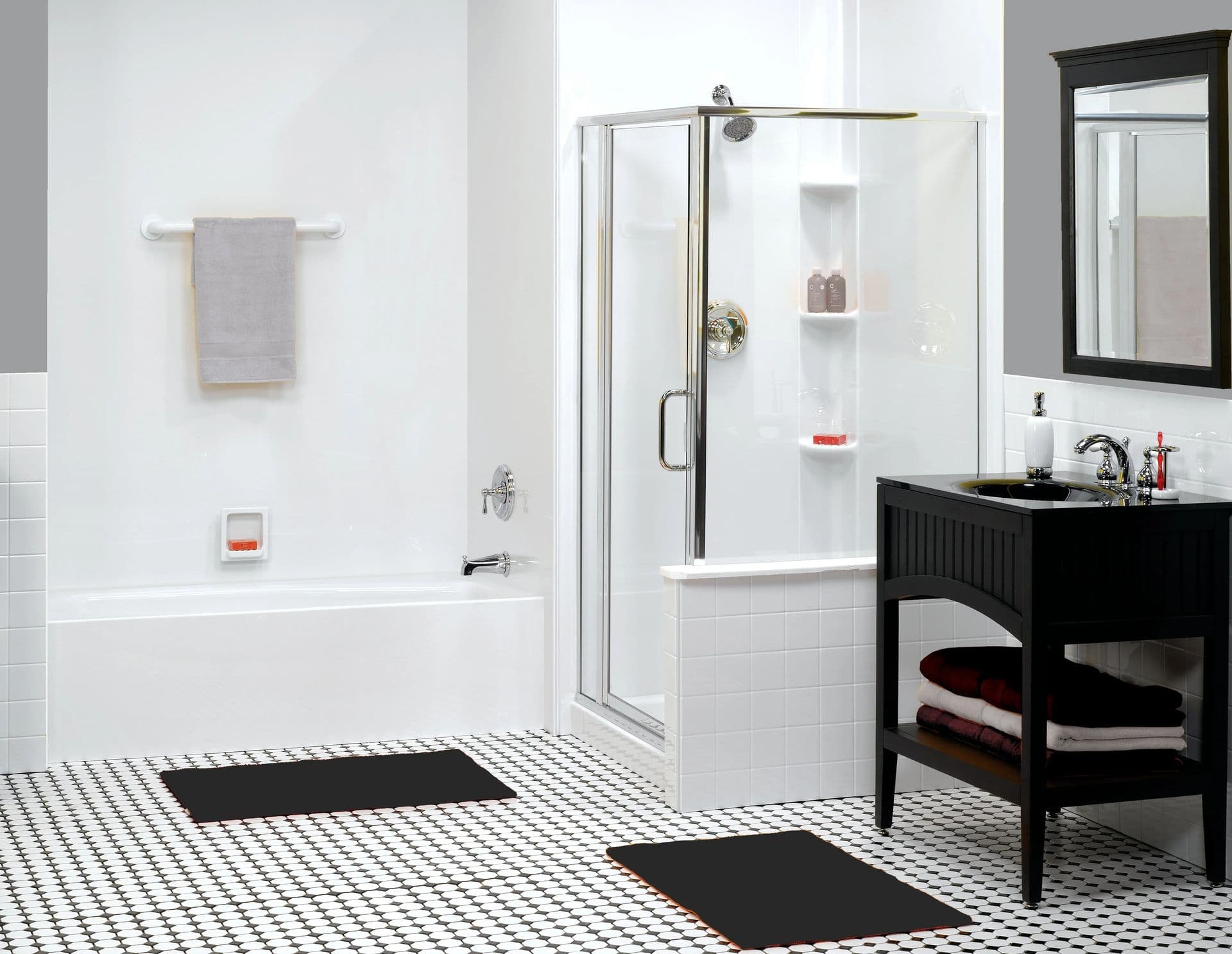 Bright, contemporary bathroom featuring a tub and shower combination with a clear glass enclosure, smooth white wall surround, built-in storage shelves, chrome fixtures, black vanity, and classic black-and-white tile flooring.